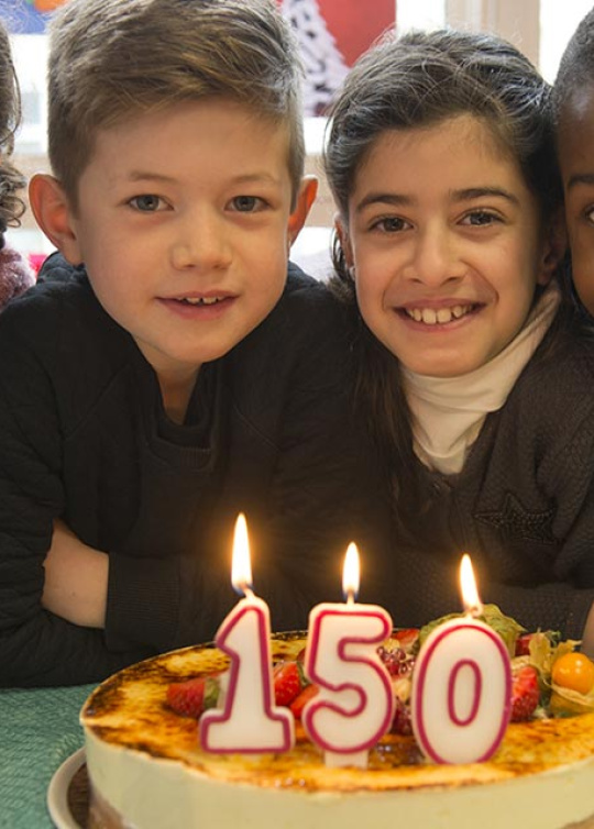 Les enfants soufflent les bougies du gâteau du 150ème anniversaire d'Apprentis d'Auteuil