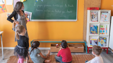 Réunis autour de leur animatrice, les enfants déchiffrent une phrase. © Lucile Barbery/Apprentis d’Auteuil. 