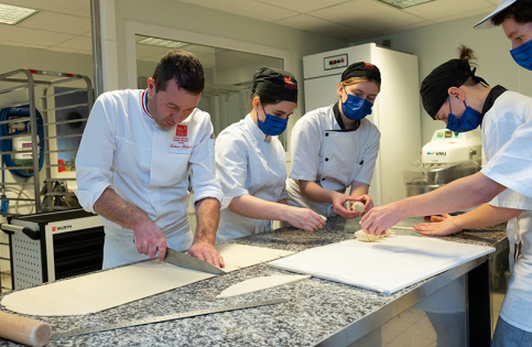 Entouré des apprentis, Ludovic Richard montre les gestes techniques du métier de boulanger. (c) Igor Lubinetsky/Apprentis d'Auteuil