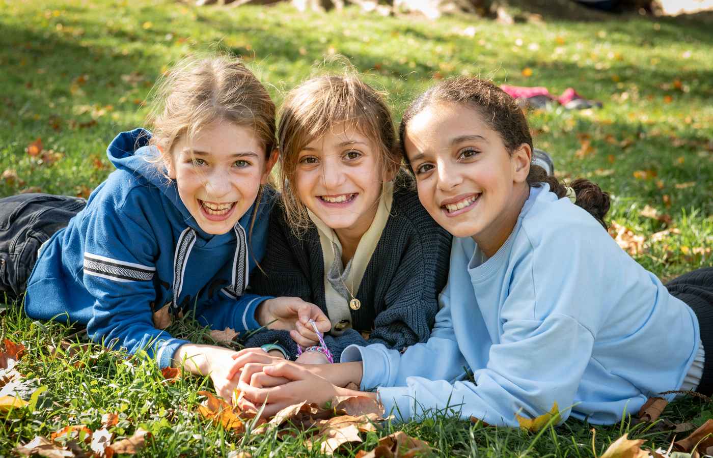3 petites filles dans un parc souriantes face à l'objectif
