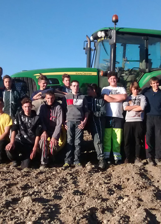 Des élèves du Lycée professionnel agricole Val de Drôme posent dans un champ devant un tracteur