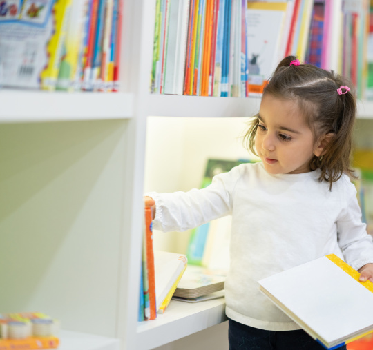 Don mensuel : petite fille bénéficiaire en crèche choisissant un livre dans une bibliothèque