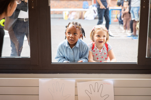 Deux fillettes devant la fenêtre d'une classe