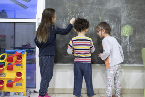 3 enfants de la Mecs Saint Martin dessinant à la craie sur un tableau noir