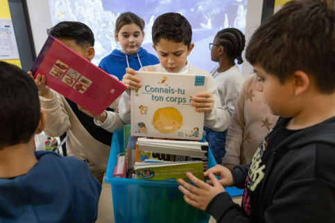 Des enfants choisissent des livres. La couverture d'un des livres est visible, son titre est : Connais-tu ton corps ?