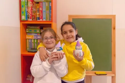 Deux petites filles souriantes tiennent des petits bonhommes de neige dans leurs mains