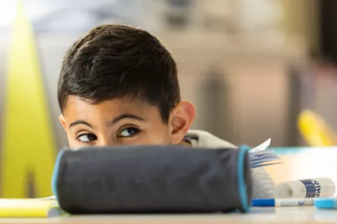 Un enfant se cache derrière sa trousse