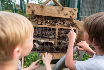 Ecologie intégrale - Deux enfants devant un hôtel à insectes