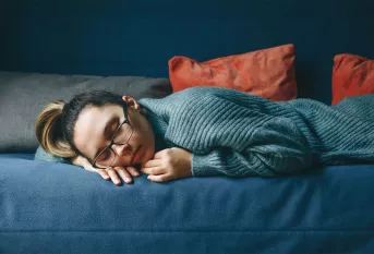 Illustration de la fatigue chez les jeunes, jeune fille dormant sur un canapé