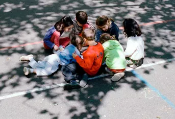 groupe d'enfants assis dans la cour de récréation
