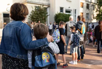 Parent et enfant de dos dans la cour d'une école