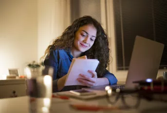 Jeune fille travaillant devant son ordinateur avec un cahier