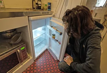 Jeune homme dans sa cuisine, devant son frigo presque vide 