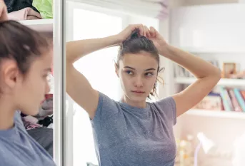Jeune fille se regardant dans la glace de sa chambre