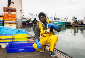 Sedou Koita, meilleur apprenti de France (MAF) Marin pêcheur, dans le port du Havre avec ses médailles