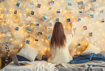 Jeune fille devant un mur de photos dans sa chambre