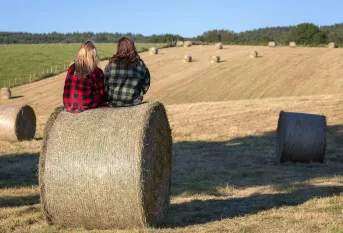 Deux jeunes femmes assises sur des meules de foin dans la campagne