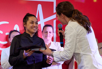 Nina Métayer remet un prix à Christine, gagnante du concours de pâtisserie