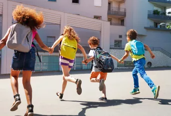 Elèves de dos courant devant leur école
