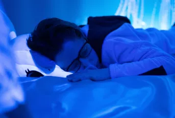 jeune garçon sur un lit dans une atmosphère bleutée