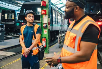 Ayoub est accompagné par la Fondation Apprentis d'Auteuil dans le cadre d'un programme d'apprentissage SKOLA "Technicien de maintenance industrielle ferroviaire". Il discute avec son tuteur d'apprentissage, Cédric Ntietie, chef de dépôt du site RATP MP14 
