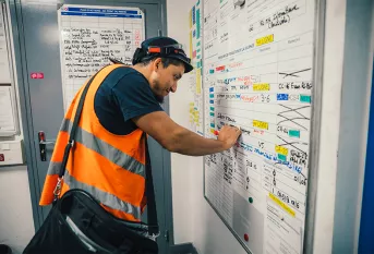 Ayoub est accompagné par la Fondation Apprentis d'Auteuil dans le cadre d'un programme d'apprentissage SKOLA "Technicien de maintenance industrielle ferroviaire". Il inscrit sa tâche de réparation sur le tableau de production de la journée sur le site de la ligne MP14 (