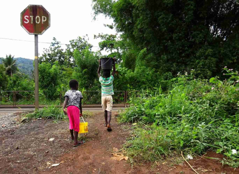 Deux enfants de dos portant des seaux d'eau