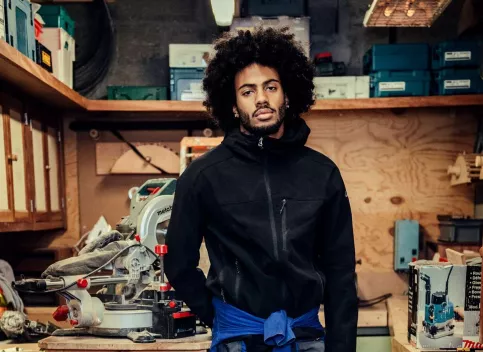 Un jeune homme se tient debout dans un atelier de menuiserie