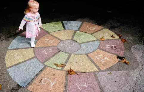 Une enfant de maternelle pendant la récréation sur un jeu peint sur le sol