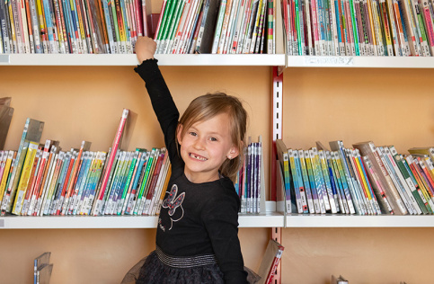 Enfant de classe primaire devant une bibliothèque de livres