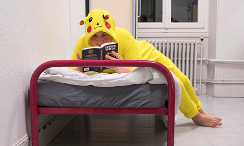 Jeune adolescent dans un internat, déguisé, lisant sur son lit