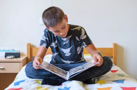 Jeune adolescent dans un internat, lisant sur son lit