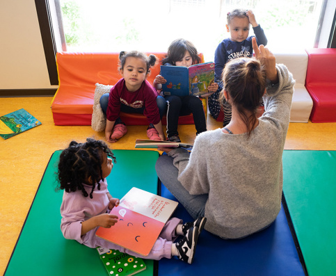 En crèche, une éducatrice fait la lecture à des petits