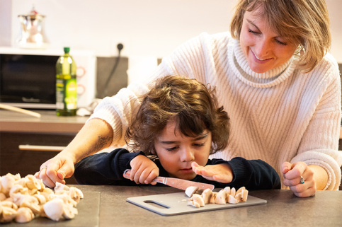 Thays, 4 ans, à l'accueil éducatif de jour Louis et Zélie Martin de Colmar coupe des champignons sous le regard de Laëtitia Simonutti, maîtresse de maison 