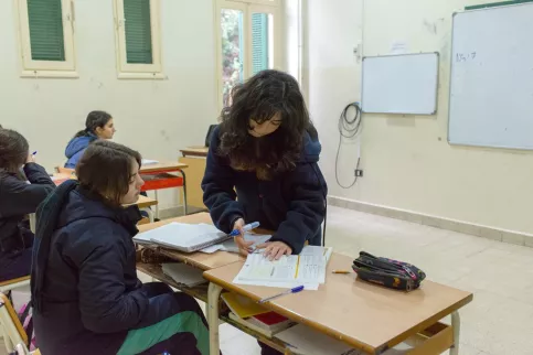 Salle de classe, une enseignante est penchée sur le bureau d'une élève