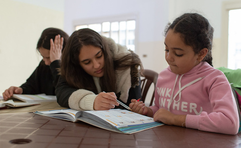 Theresia, une ancienne résidente de l'accueil de jour de Dora aide les plus jeunes à faire leurs devoirs