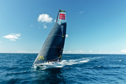 Le bateau de Violette Dorange, DeVenir, en pleine mer. On voit le logo d'Apprentis d'Auteuil en haut de la grand-voile et celui de MacDonalds en bas.