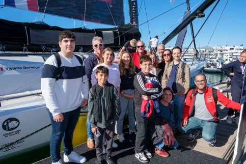 Violette Dorange au milieu d'un groupe de jeunes et adultes près de son bateau.