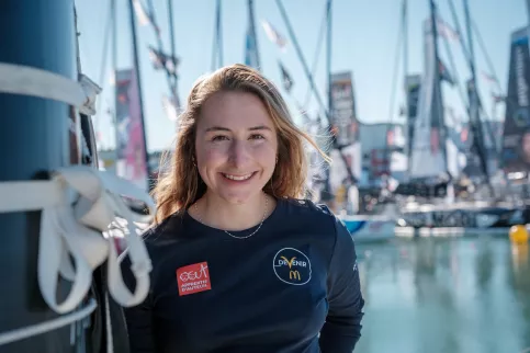 Violette tout sourire devant des bateaux du Vendée Globe