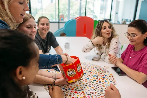 Maison des familles de Dijon - moment de jeux - à gauche Vanessa Champenois la directrice, une collaboratrice et des mamans  jouent à un jeu de société 