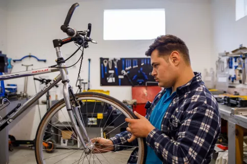 Jeune homme réparant un vélo dans l'atelier