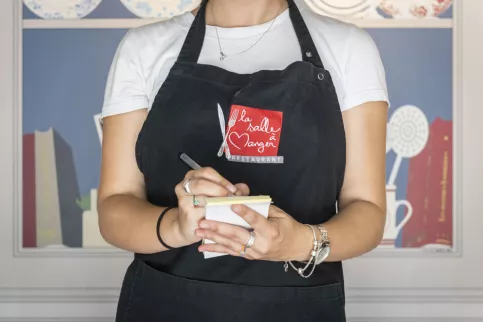 jeune femme portant un tablier de la salle à manger prenant commande