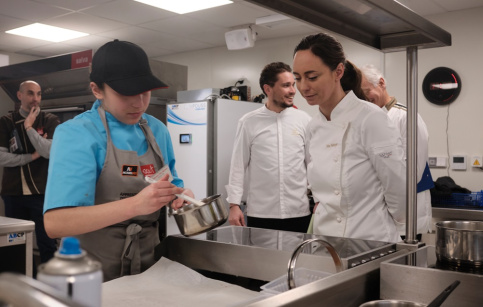 Un jeune élève tourne sa préparation dans une casserole. Nina Métayer l'observe attentivement