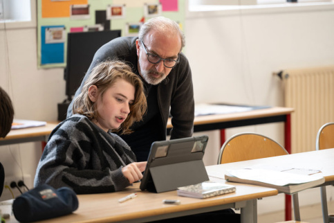 Un professionnel regarde une tablette avec l'élève en classe