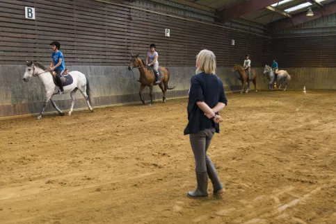 un professeur d'équitation qui enseigne aux jeunes dans un manège
