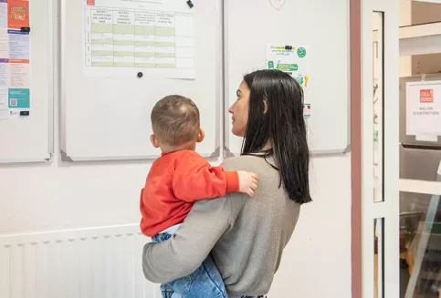 Résidence sociale St Bruno - une jeune maman avec son enfant  regarde le panneau d'affichage des activités