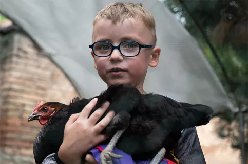 Enfant de la MECS Saint-François d'Assise de Strasbourg avec une poule dans ses bras