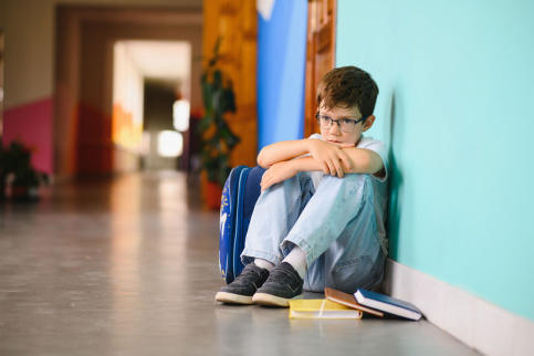 jeune garçon recroquevillé dans un couloir d'école