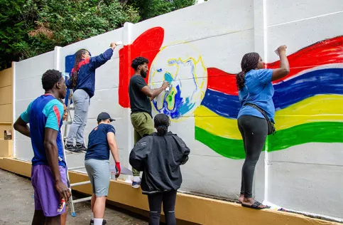 AESI - Groupe de jeunes peignant la fresque avec les drapeaux des deux pays avec l'aide de Jean-Michel, un artiste peintre et éducateur