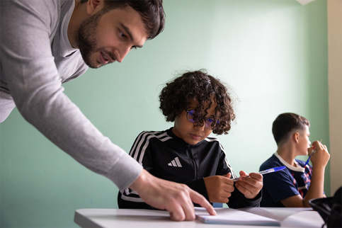 Rentrée des 6èmes au campus éducatif et écologique Saint-Philippe, Karim Ouskoulla, professeur de mathématiques, aide Wissem à remplir son carnet scolaire